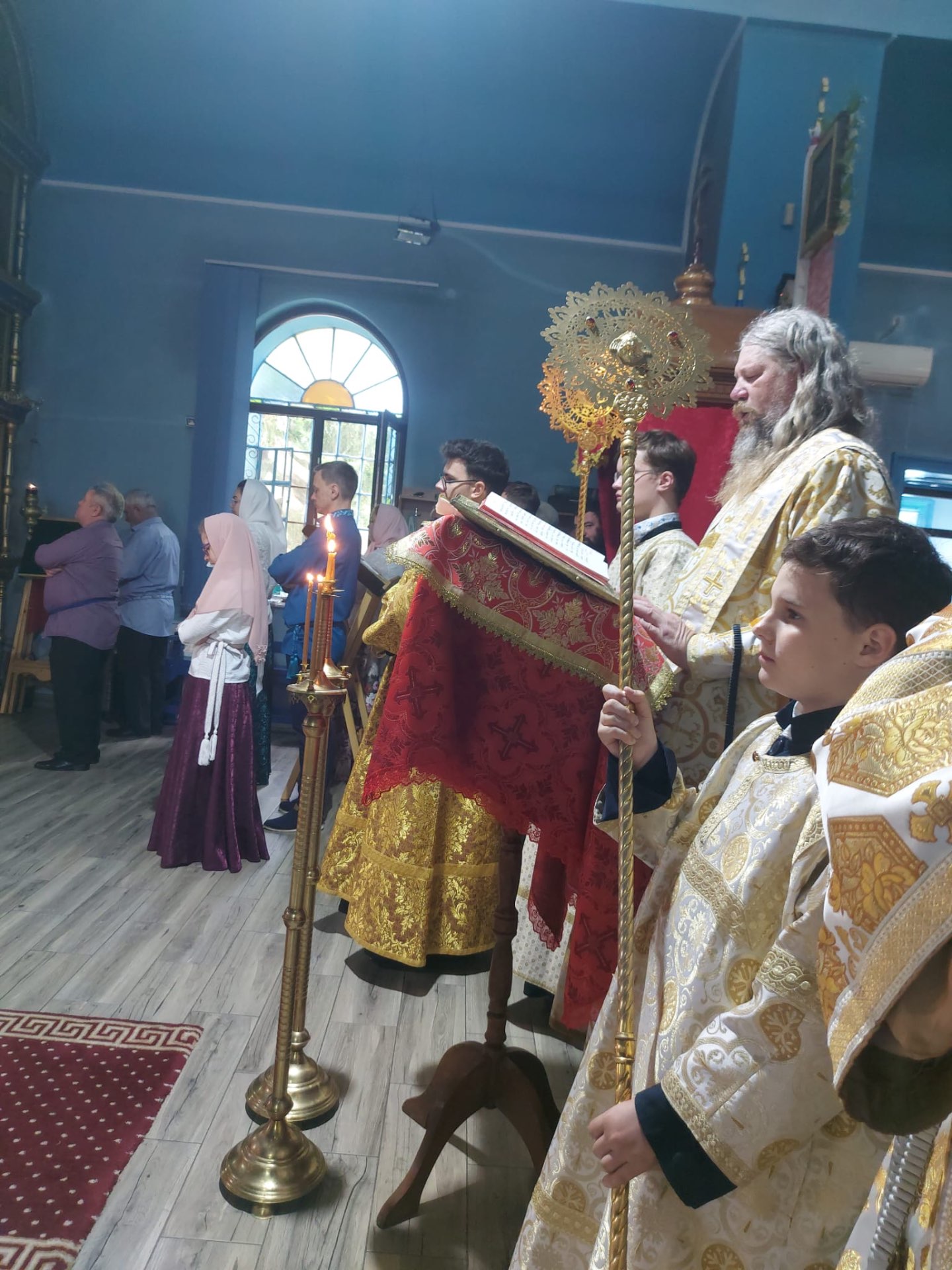 Credincioși și clerici în timpul slujbei, cu sfeșnice și Sfânta Evanghelie